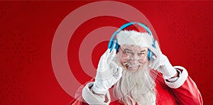 Composite image of portrait of santa claus showing hand okay sign while listening to music on headph