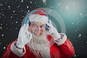 Composite image of portrait of santa claus showing hand okay sign while listening to music on headph