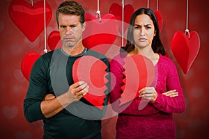 Composite image of portrait of serious couple holding cracked heart shape 3d