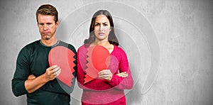 Composite image of portrait of serious couple holding cracked heart shape