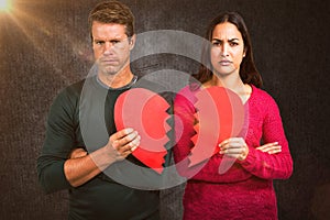 Composite image of portrait of serious couple holding cracked heart shape