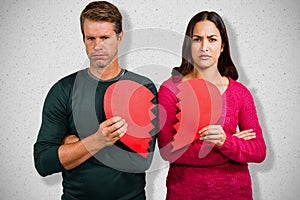 Composite image of portrait of serious couple holding cracked heart shape