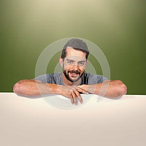 Composite image of portrait of smiling young man with cardboard against white background