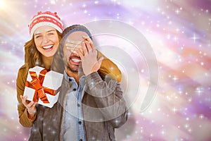 Composite image of portrait of woman giving surprise gift to man