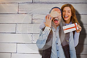 Composite image of portrait of woman giving surprise gift to man