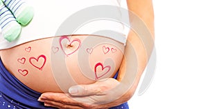 Composite image of pregnant woman holding baby shoes over bump