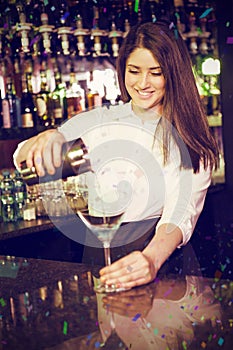 Composite image of pretty bartender pouring blue martini drink in glass