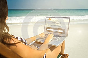 Composite image of pretty brunette using laptop on deck chair