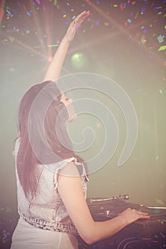 Composite image of pretty female dj waving her hand while playing music