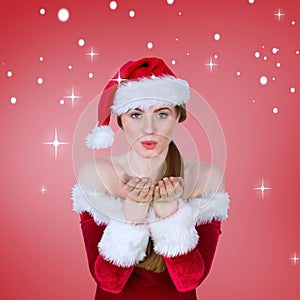 Composite image of pretty girl in santa costume blowing at camera