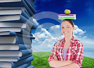 Composite image of pretty student holding an apple and books on her head