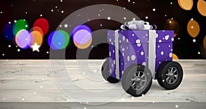 Composite image of purple wrapped with polka dot gift box on wheels