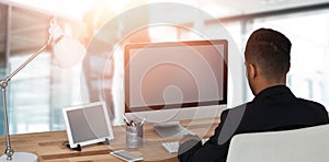Composite image of rear view of businessman working over computer