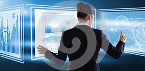 Composite image of rear view of businesswoman using imaginative digital screen