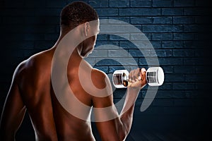 Composite image of rear view of a fit shirtless young man lifting dumbbell