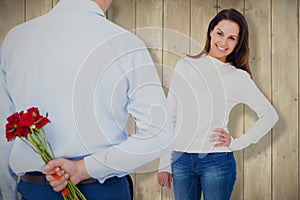 Composite image of rear view of man hiding roses behind back from woman