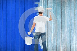 Composite image of rear view of man using paint roller