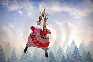 Composite image of rear view of santa claus riding on sled
