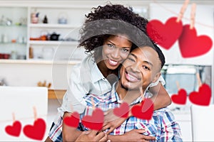 Composite image of red hanging heart and couple embracing each other