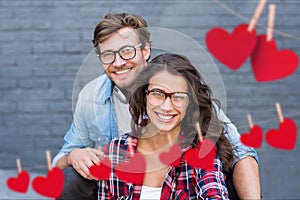 Composite image of red hanging heart and couple embracing each other