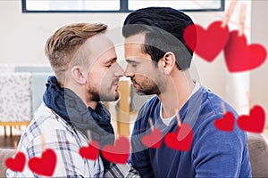 Composite image of red hanging heart and homosexual couple kissing