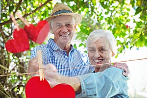 Composite image of red hanging hearts and senior couple dancing