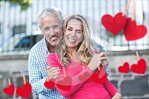 Composite image of red heart and mature couple embracing on street