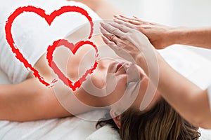 Composite image of reiki therqpist session on a woman with love hearts