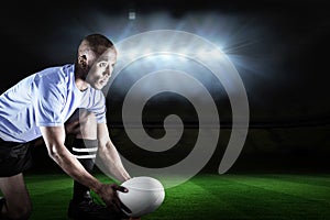 Composite image of rugby player looking away while keeping ball on kicking tee