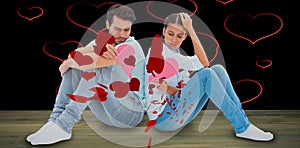 Composite image of sad couple sitting holding two halves of broken heart