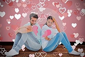 Composite image of sad couple sitting holding two halves of broken heart