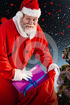 Composite image of santa claus putting christmas presents in christmas bag