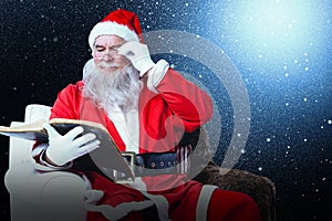 Composite image of santa claus reading bible on armchair