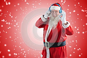 Composite image of santa claus showing hand okay sign while listening to music on headphones