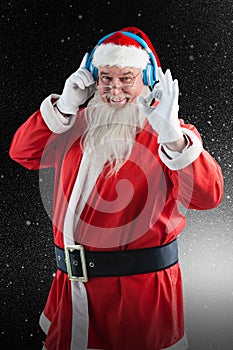 Composite image of santa claus showing hand okay sign while listening to music on headphones