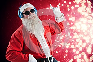 Composite image of santa claus showing hand sign while listening to music on headphones