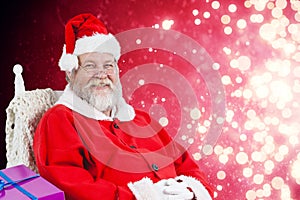 Composite image of santa claus sitting on chair with sack of christmas presents