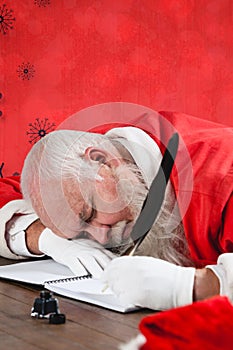 Composite image of santa claus sleeping at desk while writing letter