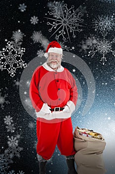 Composite image of santa claus standing with bag of gifts