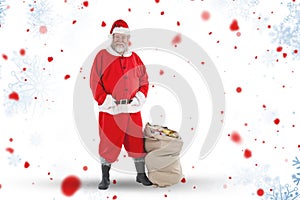 Composite image of santa claus standing with bag of gifts