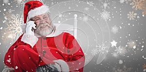 Composite image of santa claus using phone on chair