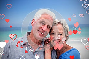 Composite image of senior couple in beach and valentines hearts 3d