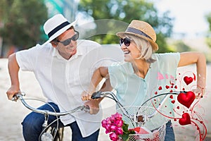 Composite image of senior couple on bike and valentines hearts 3d
