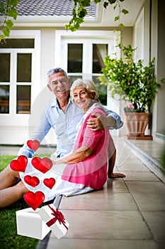 Composite image of senior couple and hearts flying from box 3d