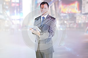 Composite image of serious charismatic businessman holding a tablet computer