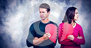 Composite image of serious couple holding cracked heart shape