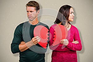 Composite image of serious couple holding cracked heart shape