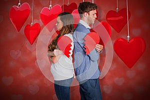 Composite image of side view of young couple holding broken heart 3d