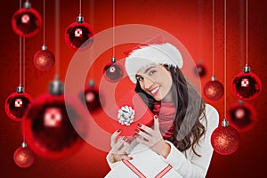 Composite image of smiling brunette holding christmas gifts