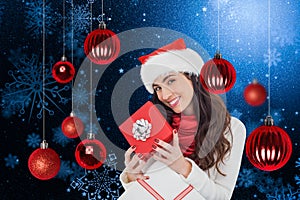 Composite image of smiling brunette holding christmas gifts